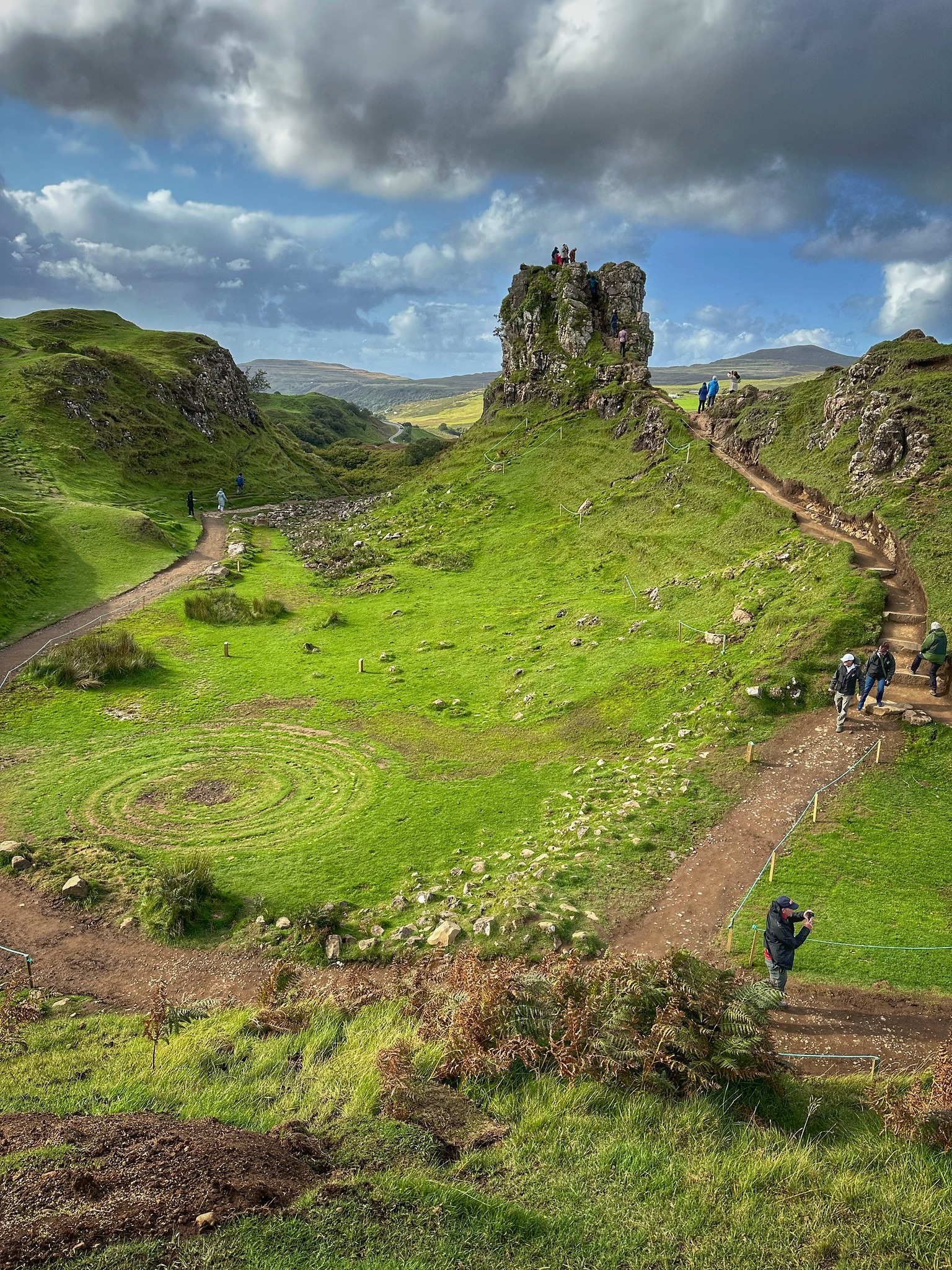 The vivid green hills and rock formations of the Fairy Glen on the Isle of Skye beneath dramatic clouds