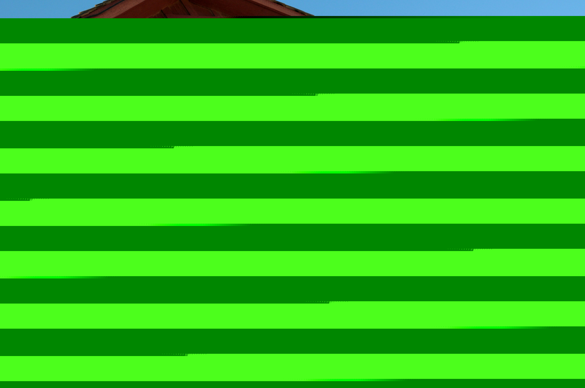 A red barn marked with four white horseshoes beneath a windmill